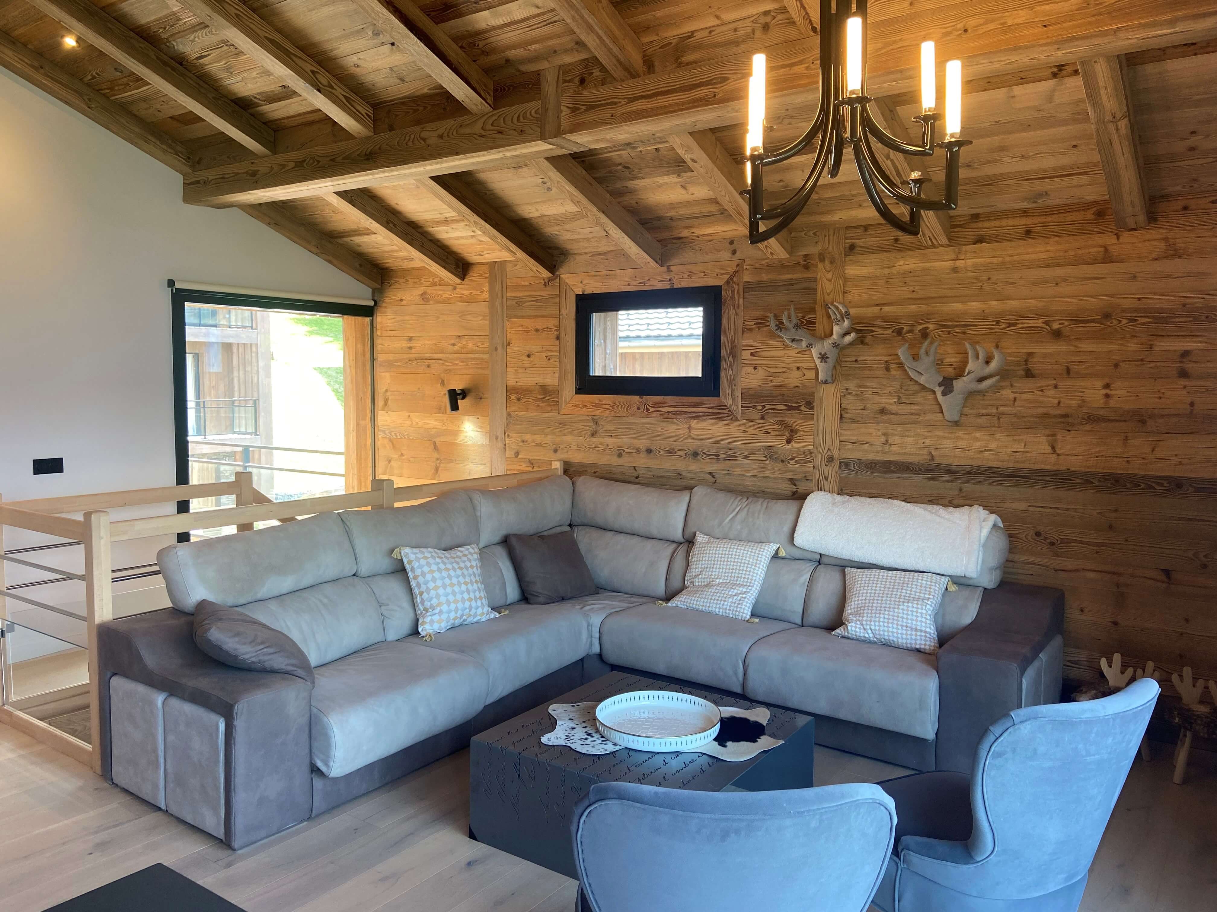 Chalet ASTRO Montalbert - Salon avec grand canapé et poutres en bois brut